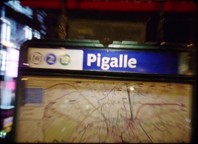 Sign and map in front of a staircase on the streets of a metropolitan area where people are walking and cars are passing by outdoors during evening time