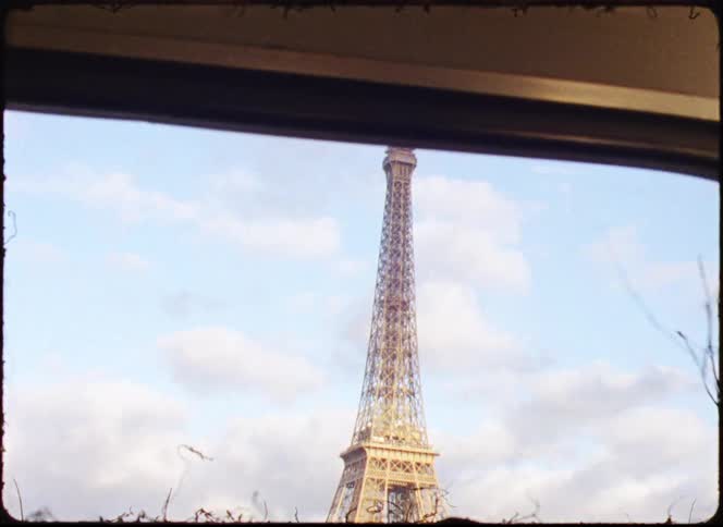 The eiffel tower seen from a boat on the river at midday with trees in the foreground
