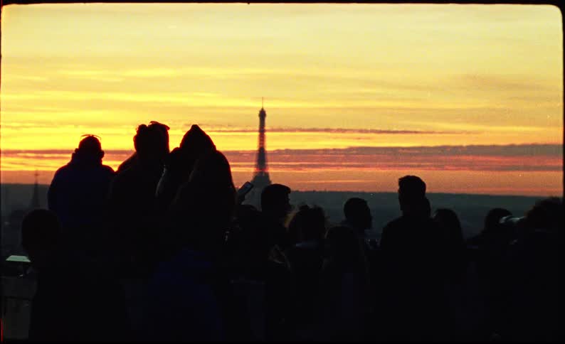 Group of people in silhouette watching the sunset with the eiffel tower in the background