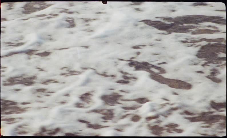 Wave with foam moving along the beach