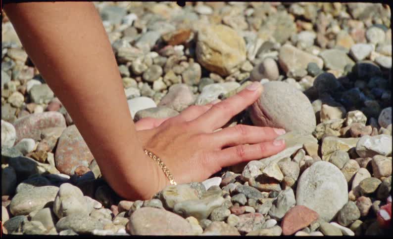 Hand with a bracelet resting on stones