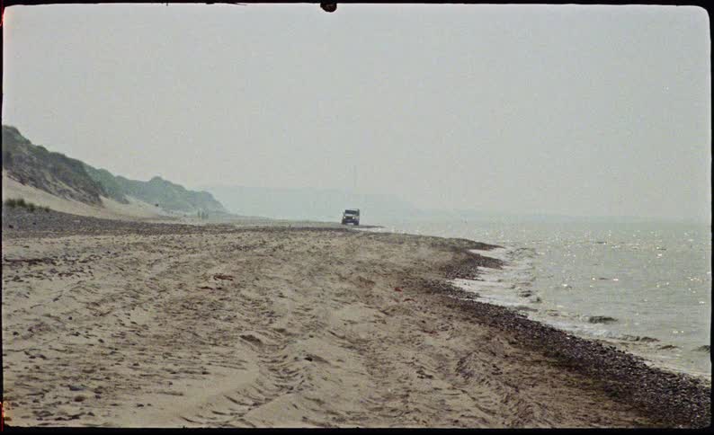 Jeep travels along the coast as waves roll in to shore and seagulls fly overhead