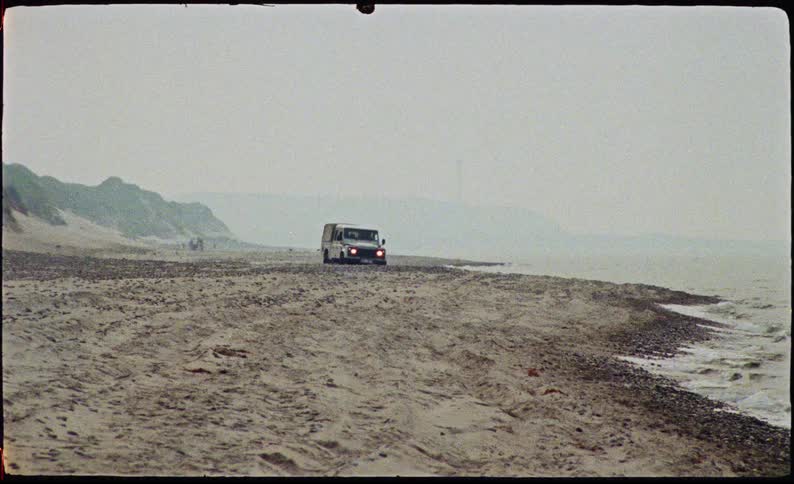 Pickup truck driving on the sandy beach on a cloudy day