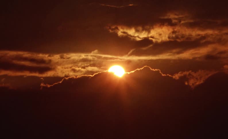 Sun shining over the clouds in a dark red sky