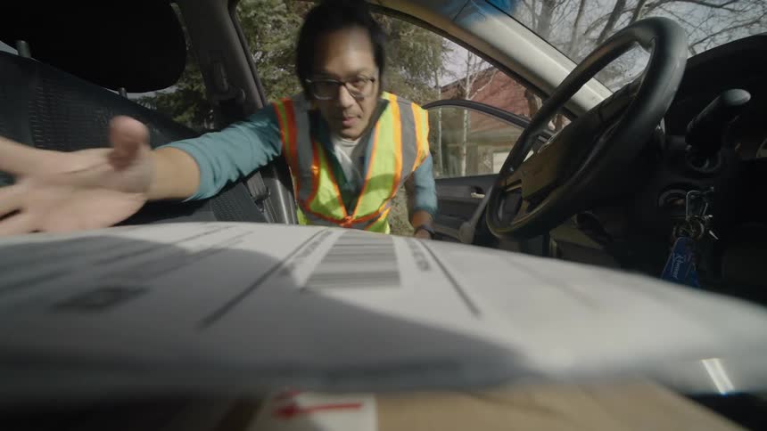 The man removes the packages from the car passenger seat