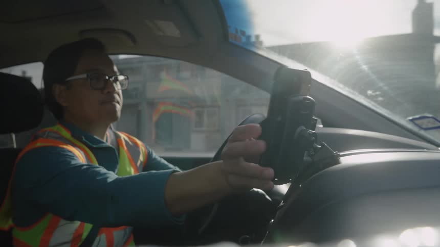 Man in reflective vest placing his cell phone in a car holder