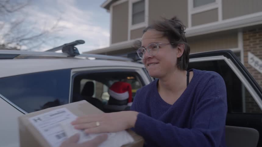 Woman receiving a box and storing it inside a car