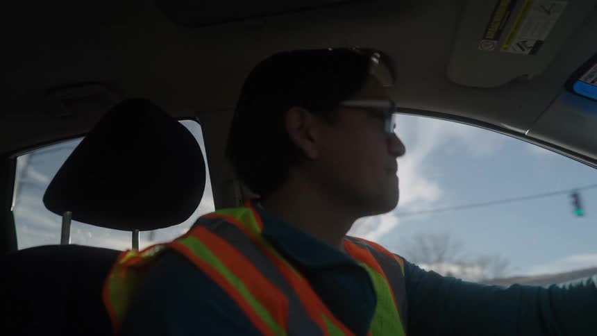 A delivery driver joyfully enjoys delivery work while driving a car during the day