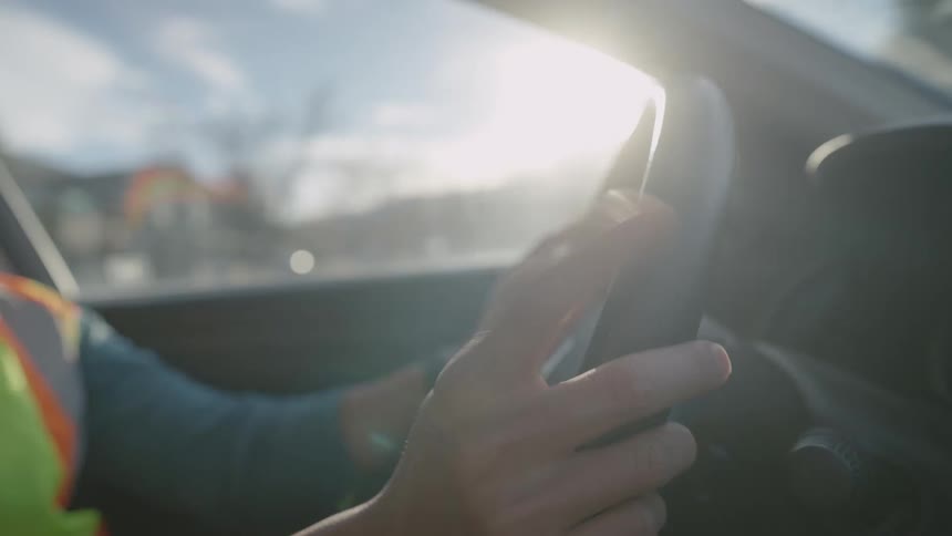 Man taps the steering wheel with his fingers as he drives through a neighborhood