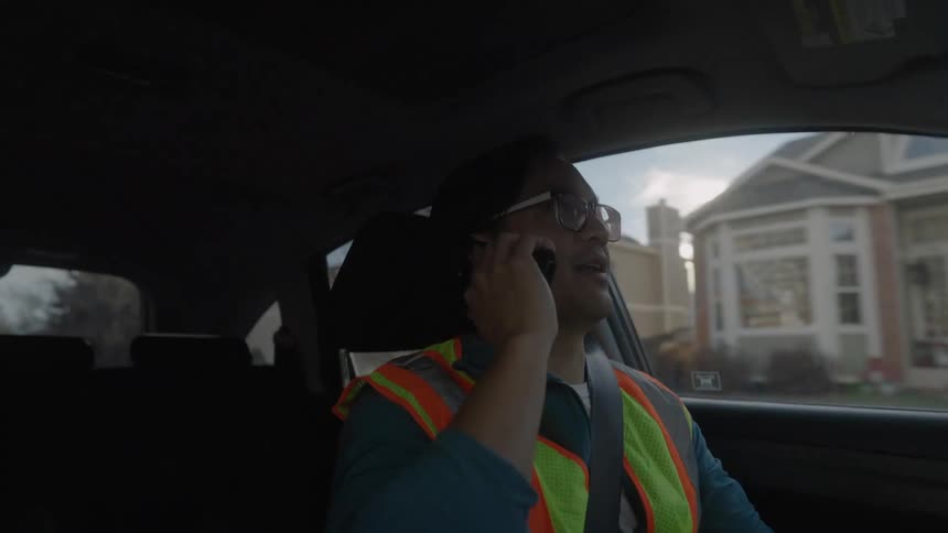 Man talks on his phone as he drives through a neighborhood
