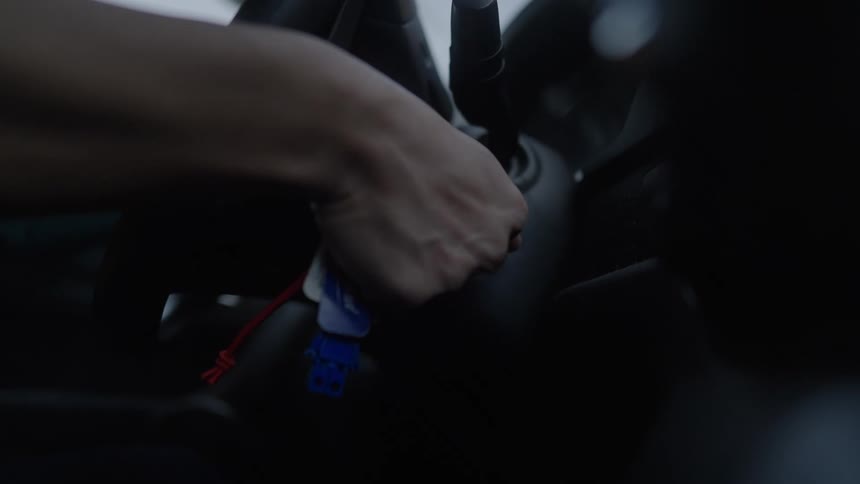 Driver turns the key in the ignition of an automobile failing to start the car