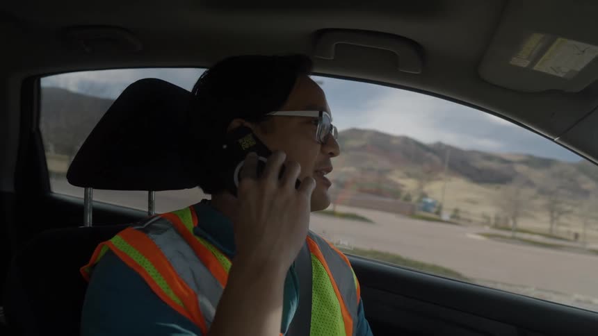 Young man talks on his phone as he drives through a neighborhood