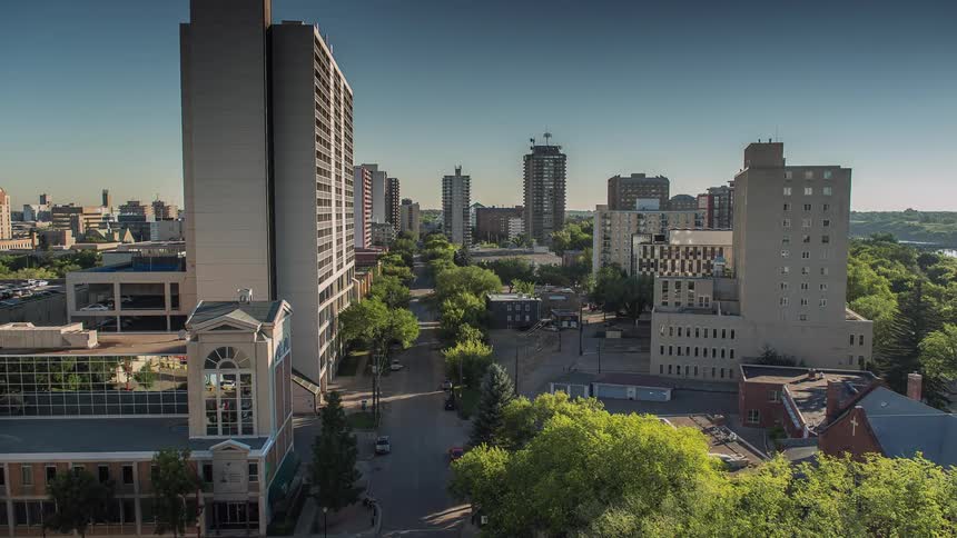 Cars travel down the street of a city with several tall buildings