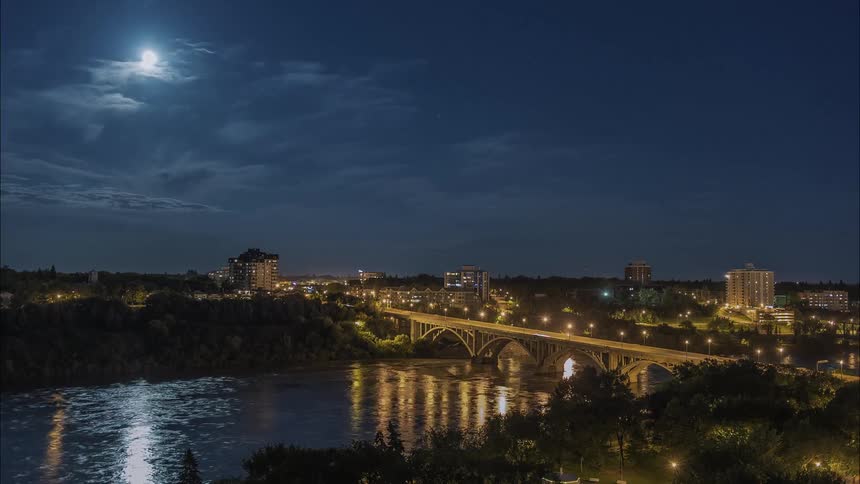 The bridge and town ahead are brightly lit at night