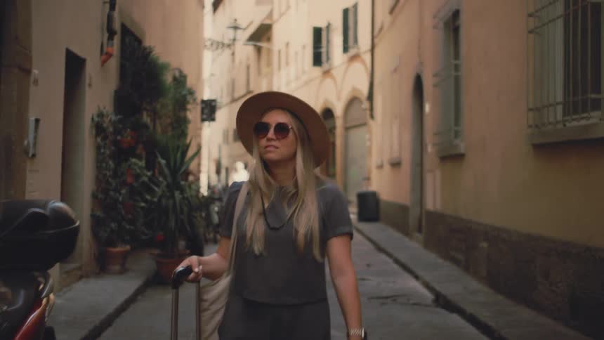 The woman drags her luggage through the city
