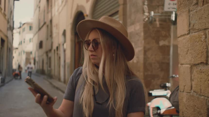 Woman standing on the street in front of buildings looking at her phone