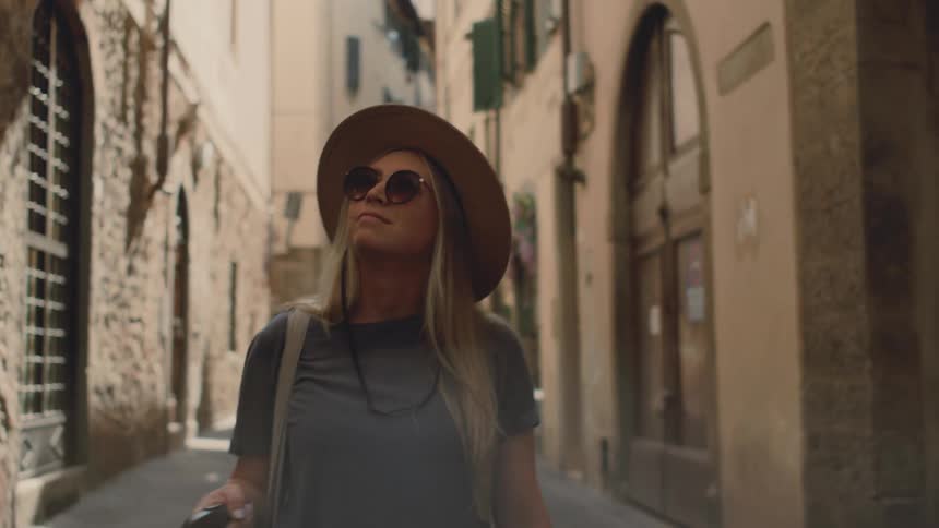 The woman is looking at the buildings in the alley