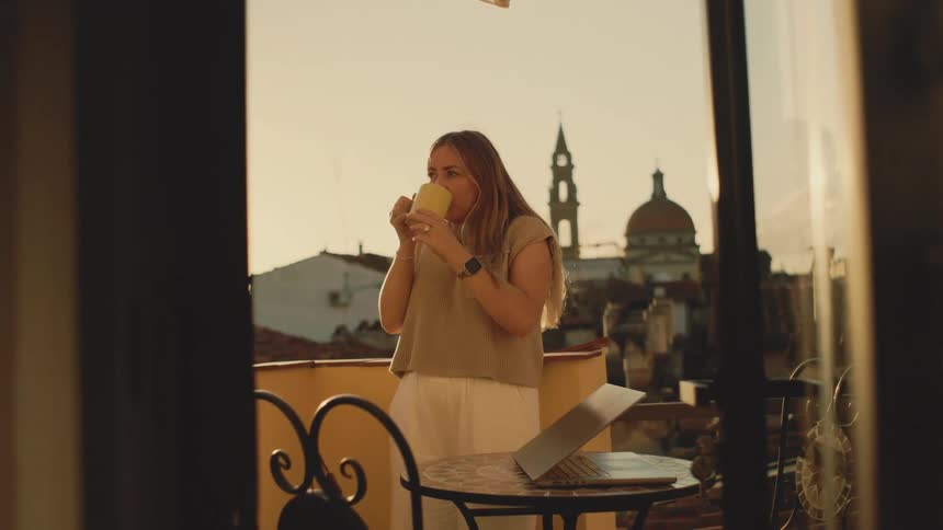 Woman on a balcony drinking from a mug