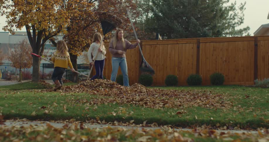 The girls are raking leaves in the yard