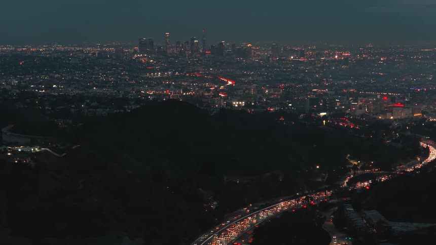 City lights glow in the darkness as heavy traffic moves on the highways
