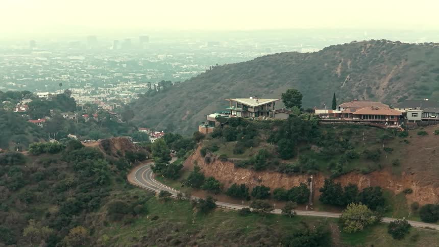 Aerial of mountaintop houses outside of a metropolis