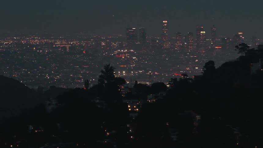 City illuminated at night viewed from an elevated point with hills in the foreground