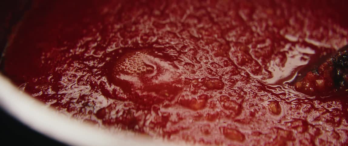 Red sauce boiling on a sauce pan indoors