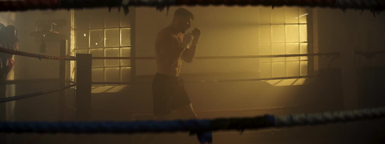 Boxer standing in the ring shadow boxing and practicing his moves
