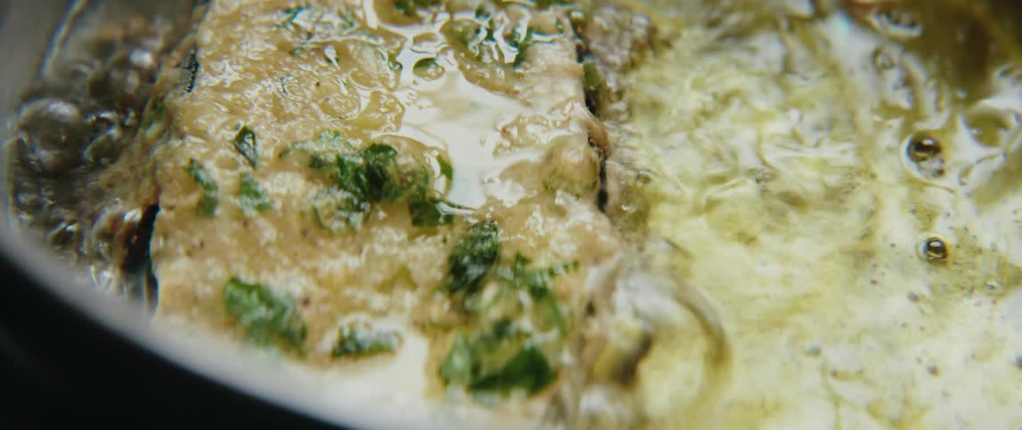 A piece of breaded food fries in hot oil sizzling and bubbling as it cooks