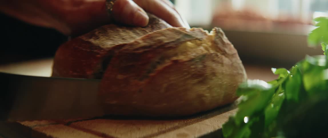 Closeup of an adult slicing a homemade bread loaf