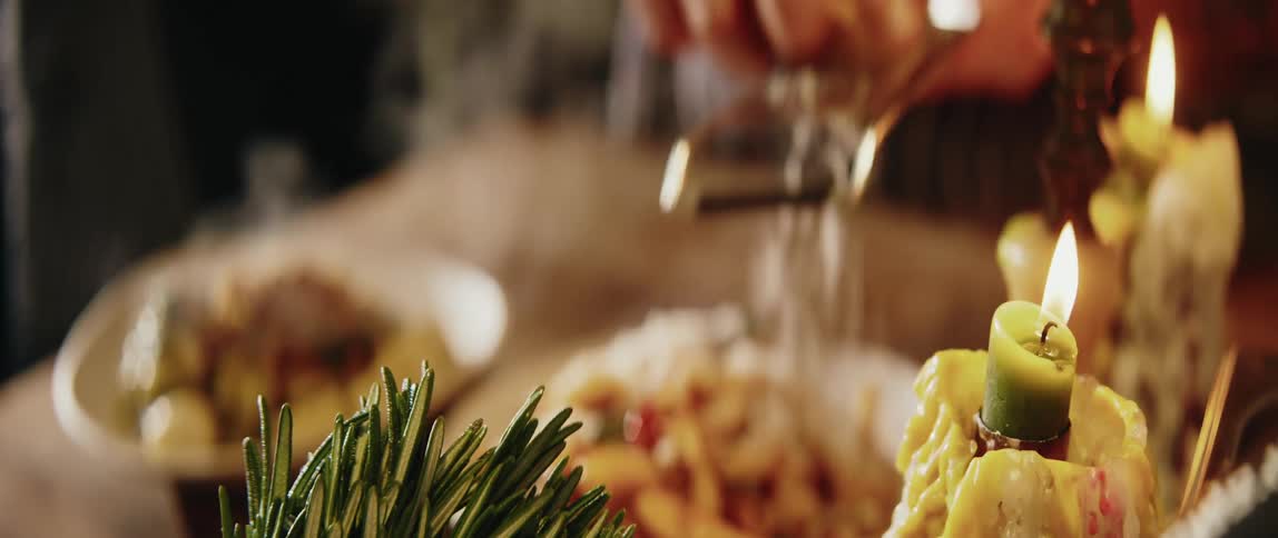 A cook grating cheese over a plate of food on a table with two lit candles beside it