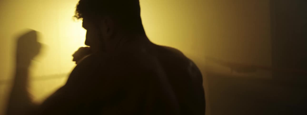 A man doing boxes punches in the air in an orange room