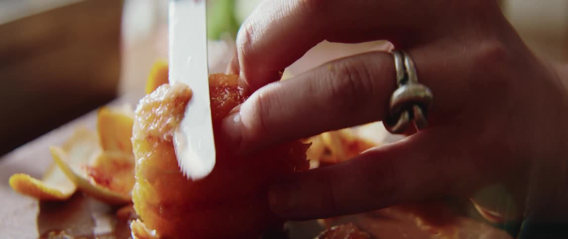 Hand cuts a piece of fruit with a knife on a preparation surface