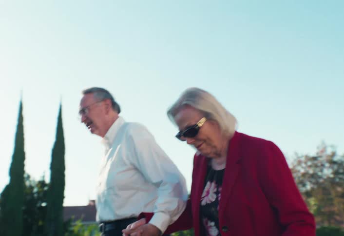 Elderly couple hold hands as they walk together in the yard