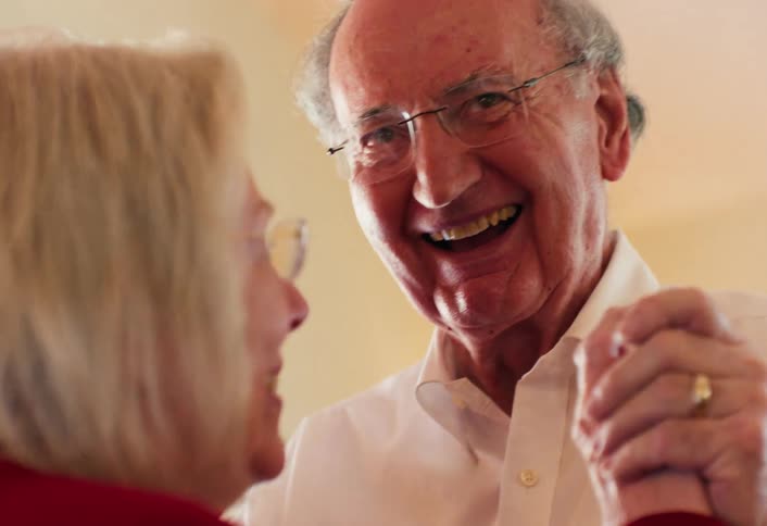 Elderly couple dancing together as he gives her a kiss