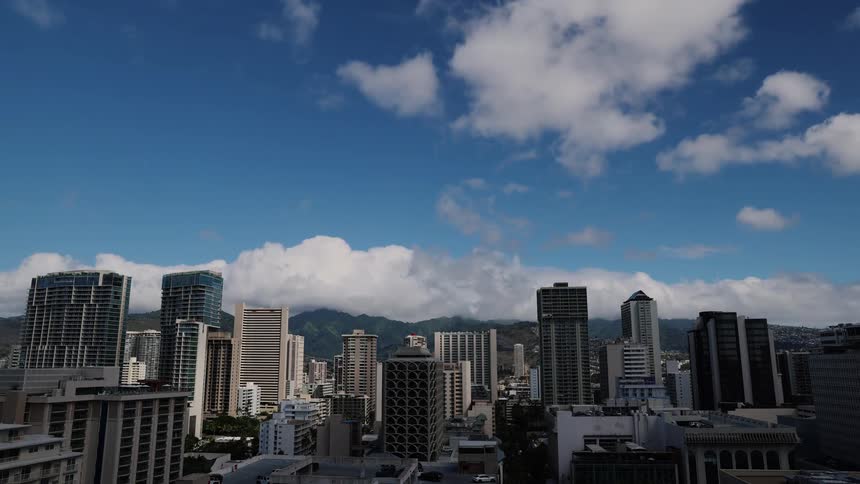 Clouds cast shadows onto a city bordering the mountains during the daytime