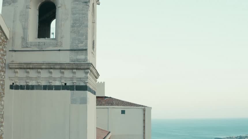 A white church with an open window and a large sea in the background