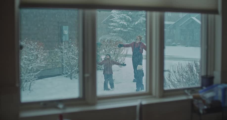 A father twirls outside in the snow with his three children