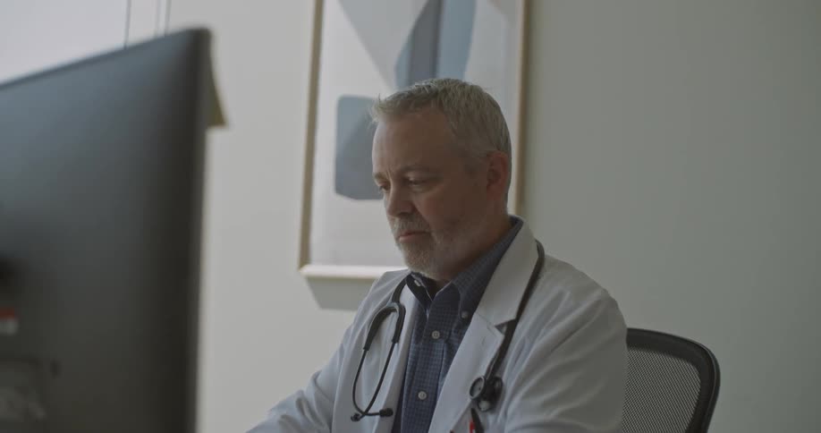 Doctor sitting at a desk typing on a laptop computer