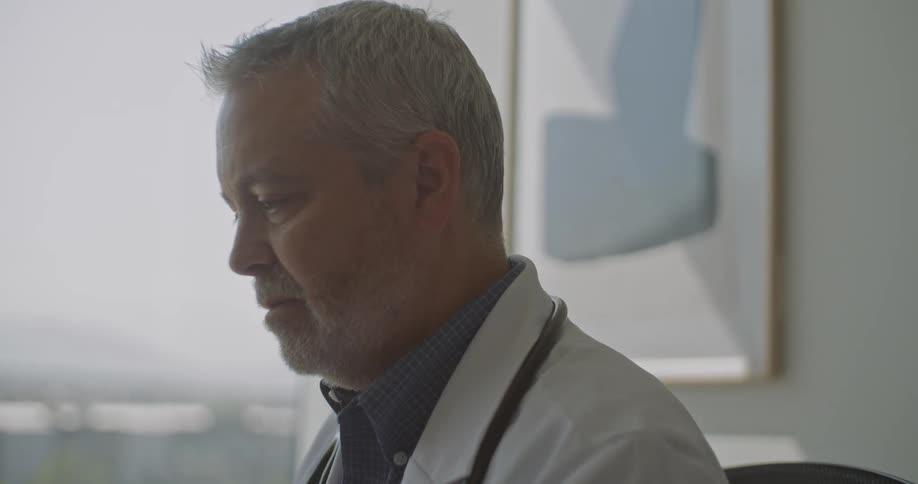 The face of a white hair man using a lab coat facing something in front of him