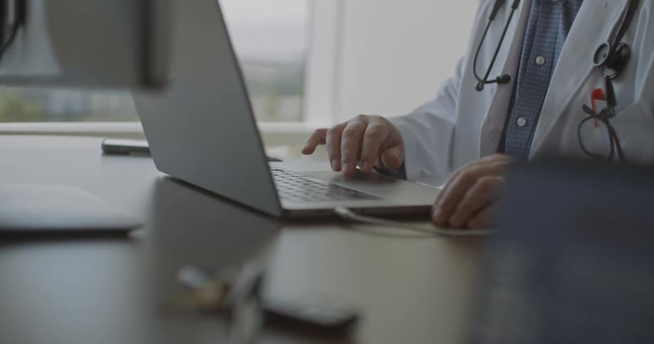 Doctor sitting at his desk working on a laptop computer