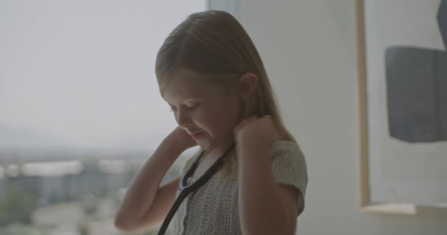 Older male doctor lets a girl play with his stethoscope during the daytime