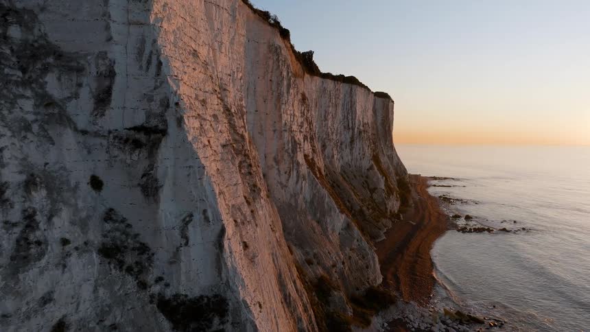 A rocky coastline at sunset with waves crashing against the shoreline