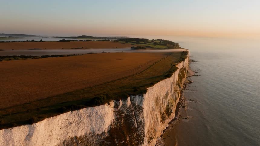 Aerial of a coastal promontory at sunset with steep vertical cliffs