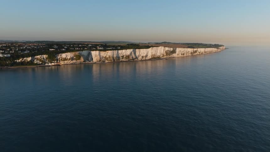 White coastal cliffs stretching along the shoreline with calm sea and clear sky