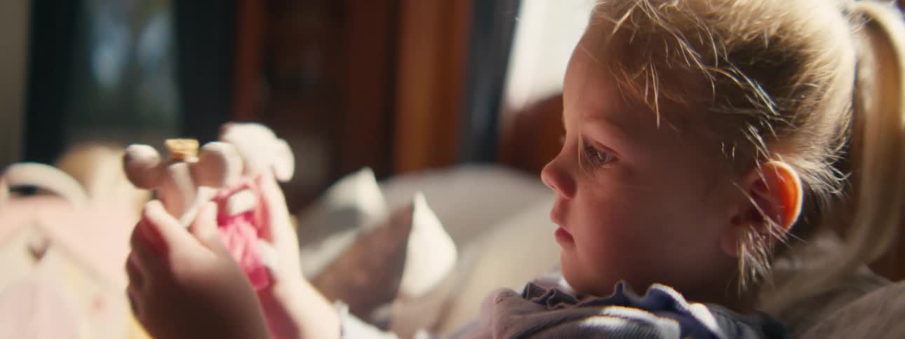 Little girl lying in bed playing with her toys