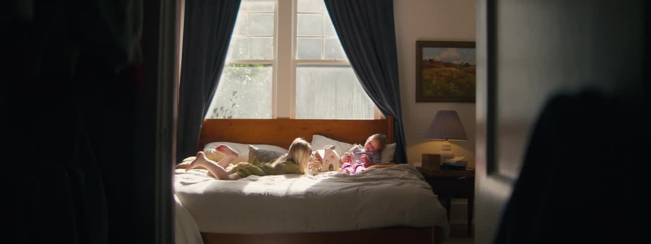 Two children playing with toys on a bed in the bedroom
