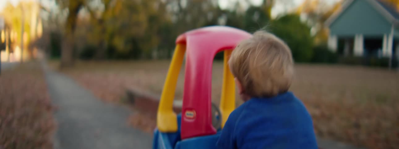 Little boy pushing his toy riding car down the neighborhood sidewalk