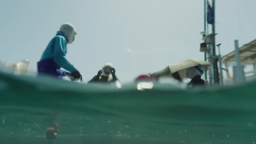 People equipped on a boat preparing gear near the sea surface in a harbor environment
