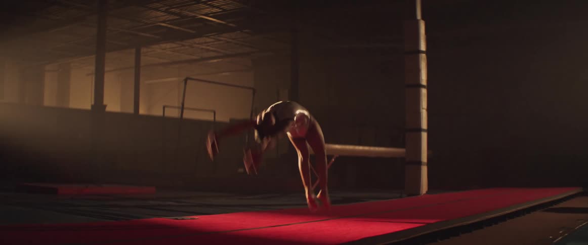 Athlete performing acrobatic back handsprings in a training gym under dramatic lighting